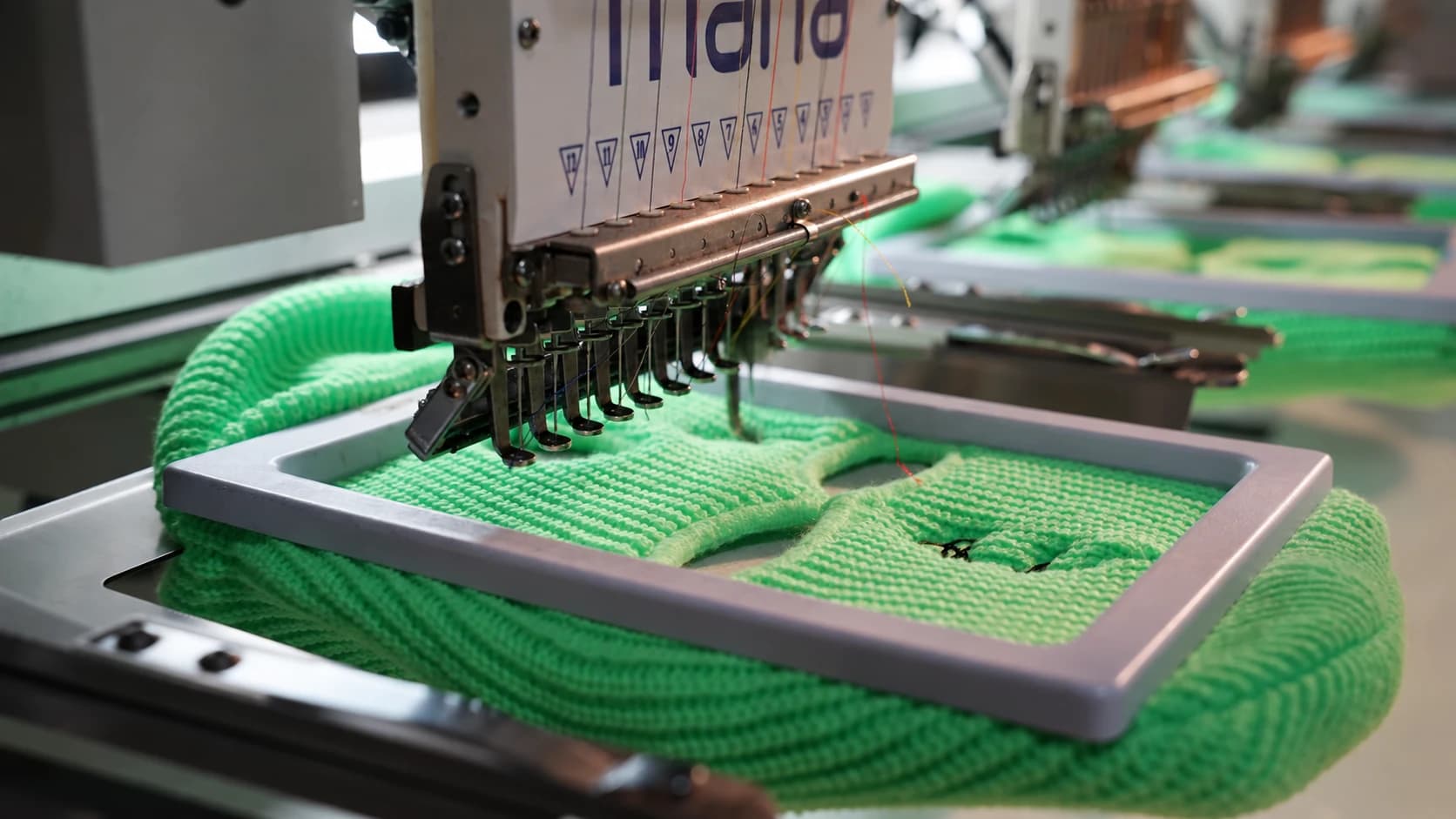 Embroidery head working on green knitted material
