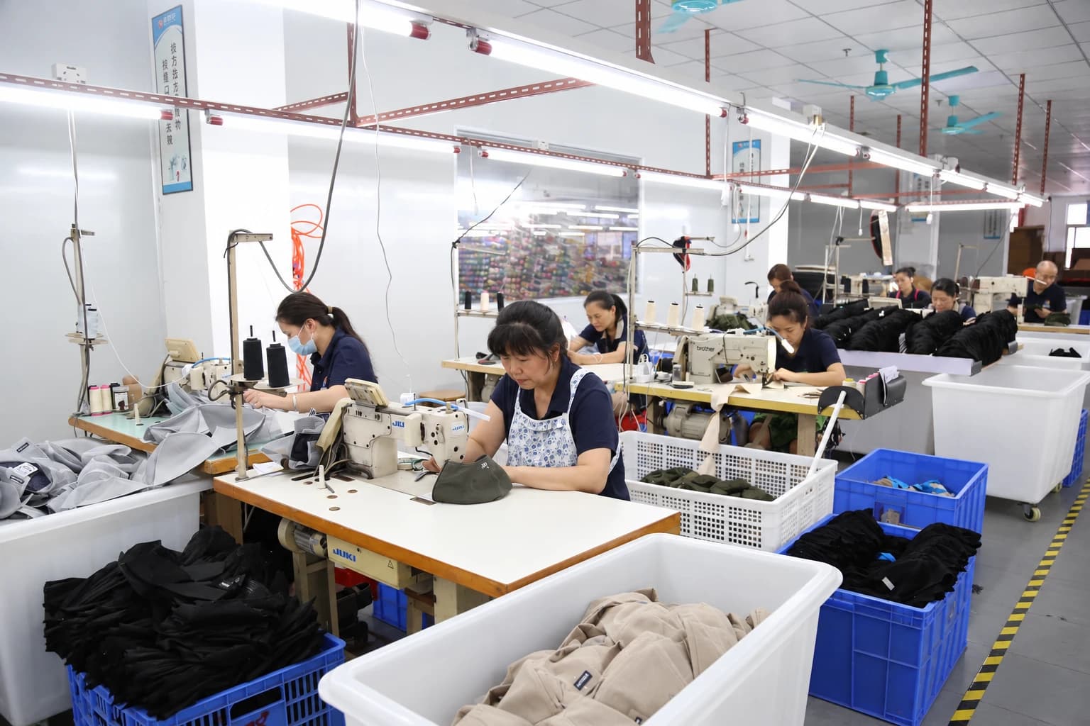 Operators sewing headwear at individual workstations